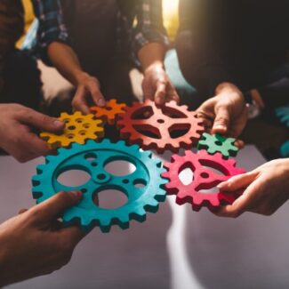 colorful gears being held by teammates in a circle